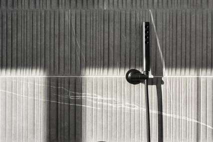 21 of 27. A sophisticated shower setup features matte black hardware set against dramatic, vertically textured tile. Sleek and minimal, this spa-inspired space blends design and function.