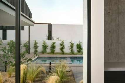 22 of 27. Framed by floor-to-ceiling glass, the desert landscaping and pool beyond become a daily visual treat. This tranquil hallway exemplifies the home s seamless indoor-outdoor connection.