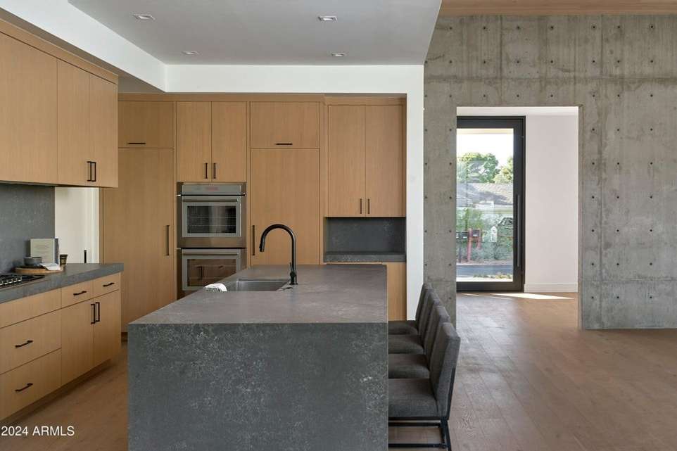 16 of 27. Natural wood cabinetry, high-end appliances, and bold quartz surfaces define this kitchen s contemporary character tailored for modern entertainers and everyday luxury.